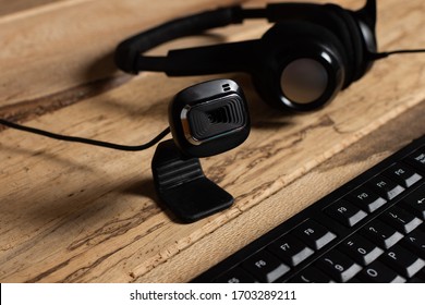 Home Office Theme: Close Up Web Cam, Keyboard And Headphones With Microphone On Wooden Desk. Concept Of Online Work And Video Calls.