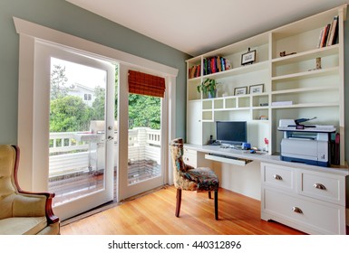 Home Office With White Open Shelves, Hardwood Floor And Blue Walls.