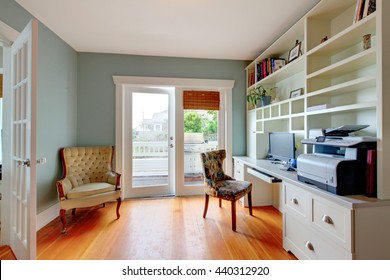 Home Office With White Open Shelves, Hardwood Floor And Blue Walls.