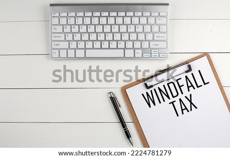 Home office workspace with keyboard, clipboard and pen with text WINDFALL TAX on a white wooden background , business concept