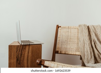 Home office workspace with laptop. Modern interior design concept. Stylish rattan wooden chair, knitted plaid. - Powered by Shutterstock