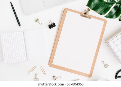Home office workspace mockup with laptop, clipboard, palm leaf, notebook and accessories. Flat lay, top view