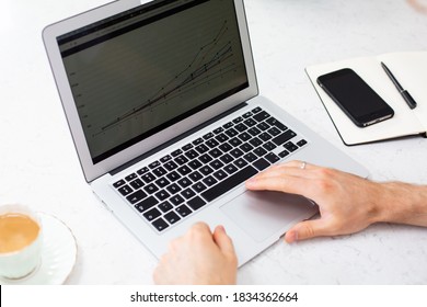 Ein Büro-Arbeitsplatz mit dünnem Laptop, Handy und Kaffee auf einem weißen Schreibtisch. Arbeiten am mobilen Computer.
