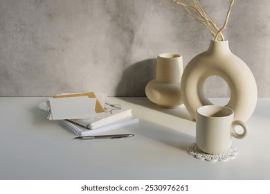 Home office workspace with vases, blank card mockup, envelope, notebooks on white table, gray wall template, Copy space. - Powered by Shutterstock