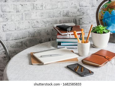 Home online school education. Stack of books , notebooks, pens, pencils, Notepad, phone, globe on the table in a bright room                              - Powered by Shutterstock