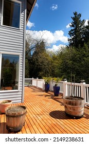 Home Outdoor Wood Backyard Deck Just Freshly Stained During Early Spring Time With Trees And Sky In Background 