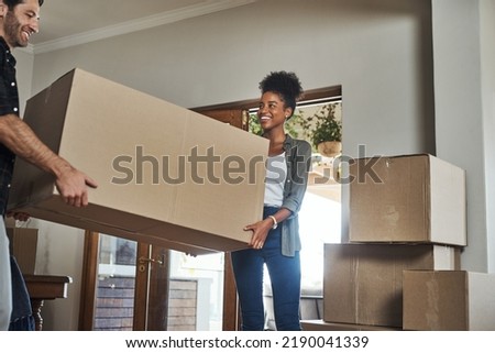 Home owner couple moving boxes into new home looking cheerful or excited inside their real estate house or living room space. Newly married first time property buyer carrying household items