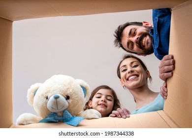 Home, People, Children, Moving And Real Estate Concept - Happy Smiling Family Opening Cardboard Box And Unpacking Belongings In New Home.