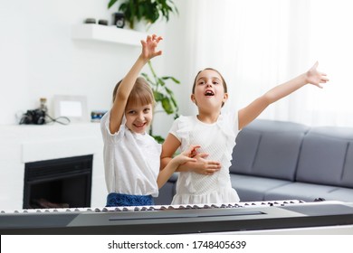 Home piano lesson. two girls practice sheet music on one musical instrument. Family concept. The idea of activities for children during quarantine.