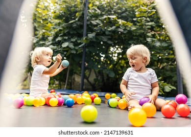 Home playroom for children. The smiling twins sit in a trampoline with a protective fence and colorful balls and play together. Sweet family moments, growing up together brother and sister - Powered by Shutterstock