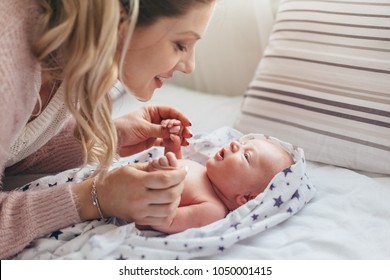Home portrait of a newborn baby with mother on the bed. Mom's care for the child.