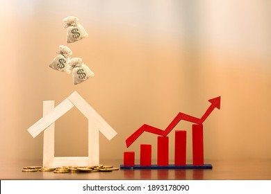 Home Put On The Coin And Red Arrow And Bar Graph With Growing Value With Drop The Money Bag On The Top Put On The Desk In The Office, Buy Or Sell A House And Real Estate For Working Capital Concept.