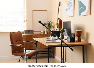 Home recording studio setup with microphone, acoustic guitar, laptop, and drum on a wooden desk