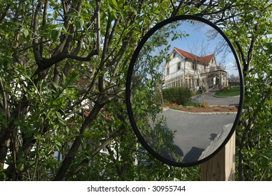 Home Reflected In Driveway Safety Mirror Helping With Obstructed View Of Oncoming Traffic.