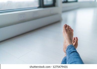 Home relax comfort lifestyle woman barefoot relaxing at warm radiators heat system in apartment or condo living. Cozy winter electric baseboards in house. Closeup of feet.