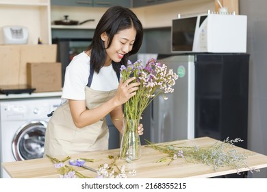 Home Relaxation Concept, Young Woman Take Care Fresh Flowers In Vase On Table In Kitchen Room.