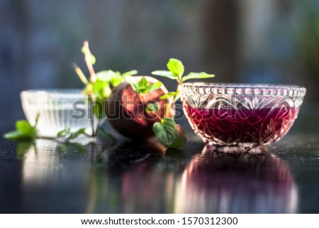 Home remedy for dandruff on wooden surface i.e., beetroot stock well mixed with water in a glass bowl along with some freshwater and raw sliced beetroot. Horizontal shot with blurred creamy bokeh.