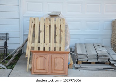 Home remodel construction pile with material and trash old cabinet door and wood pallet stacked on driveway in front of garage door
