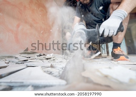 Home renovation project with man removing floor tiles