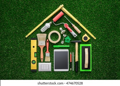 Home Renovation, Remodeling And DIY Concept, Work Tools And Tablet Composing A House Shape On The Grass