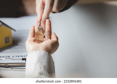 A home rental company employee is handing the house keys to a customer who has agreed to sign a rental contract, explaining the details and terms of the rental. Home and real estate rental ideas. - Shutterstock ID 2232896381