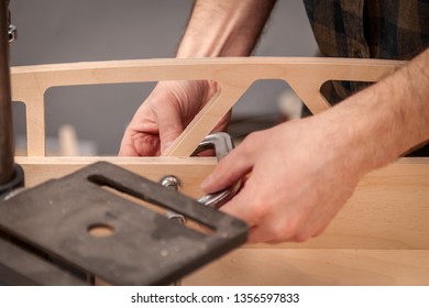 Home repair concepts, close up. Handicraft Carpentry. Cabinet-maker hands tightens the nuts  on wooden board with a clamp on the working table in the workshop