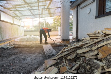 Home repair. Rebuilding waterproofing and insulation of a terrace – roof, removal and stacking of the old insulating (polyurethane). Backlit worker with pickaxe