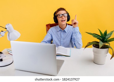 Home Schooling And Distance Education For Children. Thoughtful Smart Student Sitting At The Table, Learning By Video Link With The Teacher, On A Yellow Background