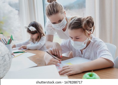 Home schooling learning during virus pandemic - pretty white woman with two children drawing in the living room, wearing surgical face masks to protect them from the virus.