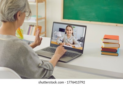 Home schooling. Mature teacher talking to little girl on laptop from classroom. Tutor communicating with pupil online - Powered by Shutterstock