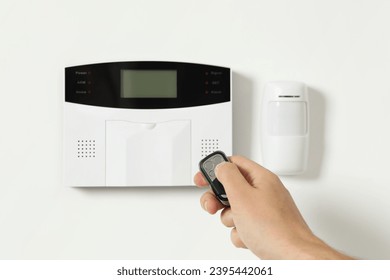 Home security system. Man using alarm key fob indoors, closeup - Shutterstock ID 2395442061