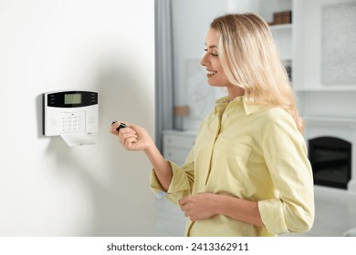 Home security system. Smiling woman using alarm key fob in room
