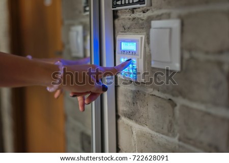 Home security system. Woman entering password on home alarm keypad