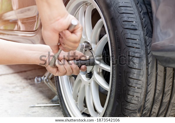 Home service car concept : A man repairing\
action lock bolt of car wheel for check the car\'s drive system\
basic maintenance that can be made by\
yourself