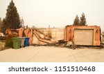 home severely burned with walls leaning and stucco hanging in the recent wild fire fire storm in Redding, California. Smoke and ash in the air as the fire continues to burn several miles away.