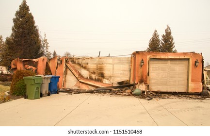 Home Severely Burned With Walls Leaning And Stucco Hanging In The Recent Wild Fire Fire Storm In Redding, California. Smoke And Ash In The Air As The Fire Continues To Burn Several Miles Away.