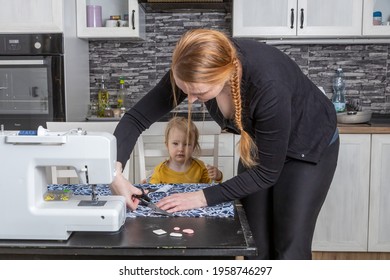 Home Sewing Concept. Young Woman Cuts The Fabric Together With Her Son. Horizontally. 