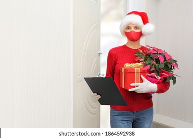 Home shopping delivery a woman wearing a Santa Claus helper hat, gloves and a protective mask delivers packages during the COVID-19 outbreak and Christmas holidays . - Powered by Shutterstock