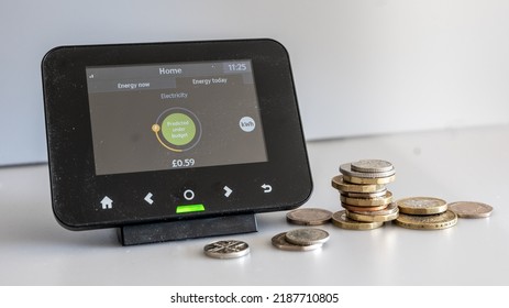 Home smart meter displaying low consumption of electricity with some coins around - Shutterstock ID 2187710805
