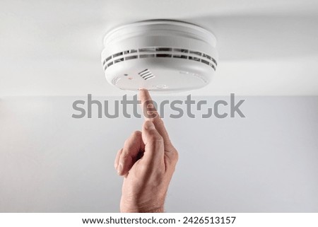 Home smoke and fire alarm detector maintenance man pushing button checking, testing or replacing battery Stock photo © 