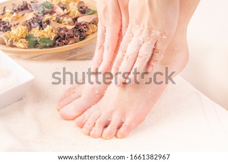 Home SPA. Young woman doing foot peeling, scrub using natural cosmetics.