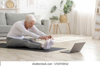 Home Sport. Active Senior Woman Doing Warming Stretching Exercises In Front Of Laptop, Training With Online Tutorials