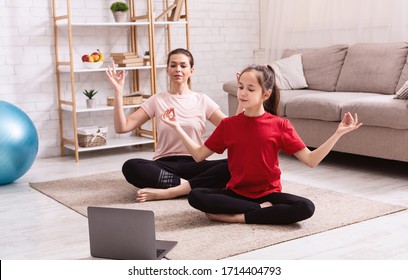 Home Sports. Mother And Daughter Doing Yoga Or Meditation While Watching Online Tutorial On Laptop Indoors