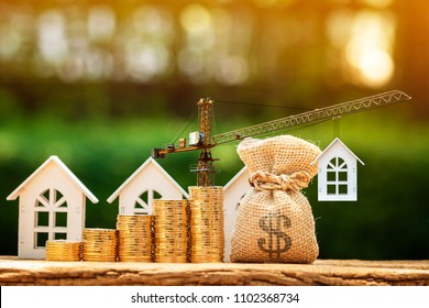 Home and stacking gold coins with increase and tower crane and hoist brake solutions with money bag to build new house in the public park, saving money and loan for construction real estate concept.