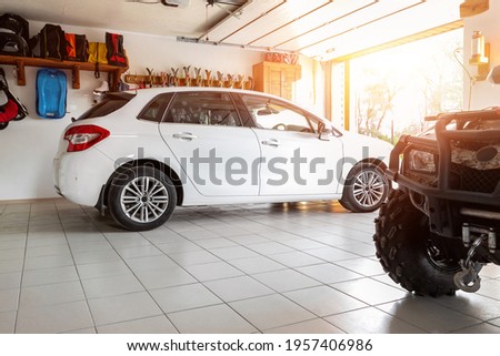 Home suburban countryside modern car and ATV double garage interior with wooden shelf, tools and equipment stuff storage warehouse indoors against sun light. Vehicle parked house parking background