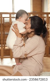 Home Sweet Home: A radiant mother savors a blissful moment as she hugs and kisses her toddler, illuminating a cozy wooden interior with her love