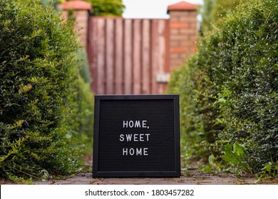 "Home sweet home" sign on black letterbox standing in the doorway next to the house entrance door.