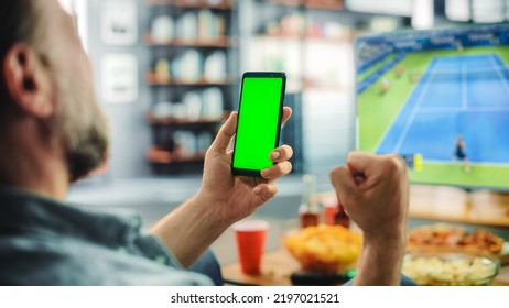 At Home Tennis Fan Celebrates Athlete's Success, Holds Green Screen Chroma Key Smartphone, Friends Watch Game on TV, Cheer for Favourtite Sportsperson to Win Championship. Screen Shows Real Game. - Shutterstock ID 2197021521