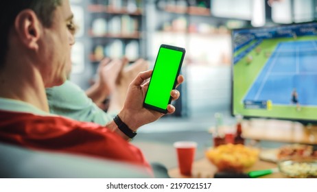 At Home: Tennis Fan Holds Green Screen Chroma Key Smartphone, with Friends Watches Intense Game on TV, Cheer for Favourite Sportswoman to Win Championship. World Cup Competition. Over the Shoulder. - Powered by Shutterstock