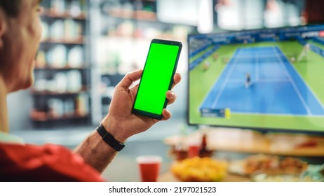 At Home Tennis Fan Holds Green Screen Chroma Key Smartphone, with Friends Watches Intense Game on TV, Cheer for Favourite Sportsperson to Win Championship. World Cup Competition. Over the Shoulder. - Powered by Shutterstock